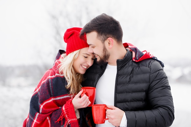 Young beautiful couple at a picnic in winter they drink coffee