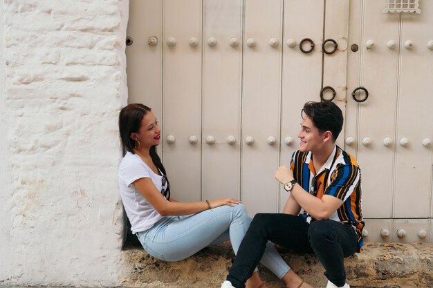 Young beautiful couple sitting on the ground in city near wall