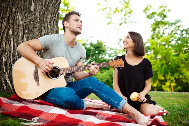 Young beautiful couple smiling resting on picnic in park