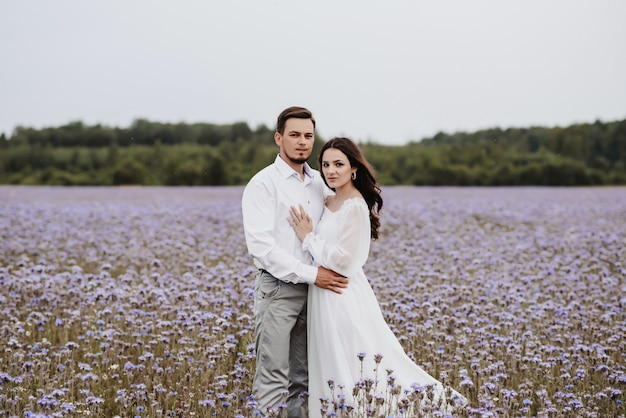 Young beautiful couple standing in a blooming purple field