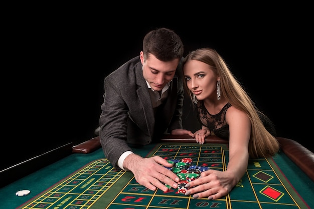 Young beautiful couple takes their winnings at the roulette table at the casino