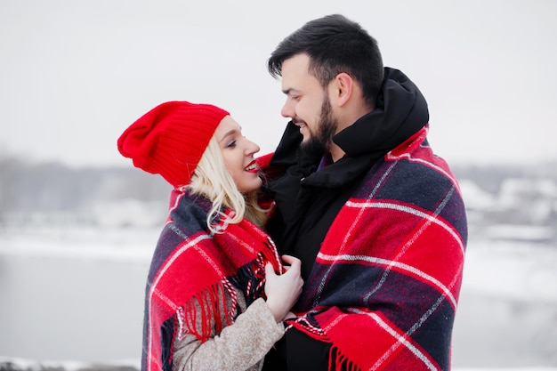 Young beautiful couple took refuge in a warm blanket on the street