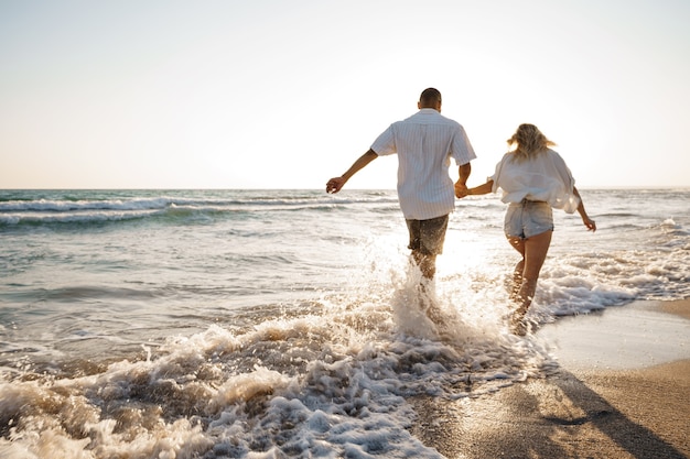 Young beautiful couple walking on beach near sea