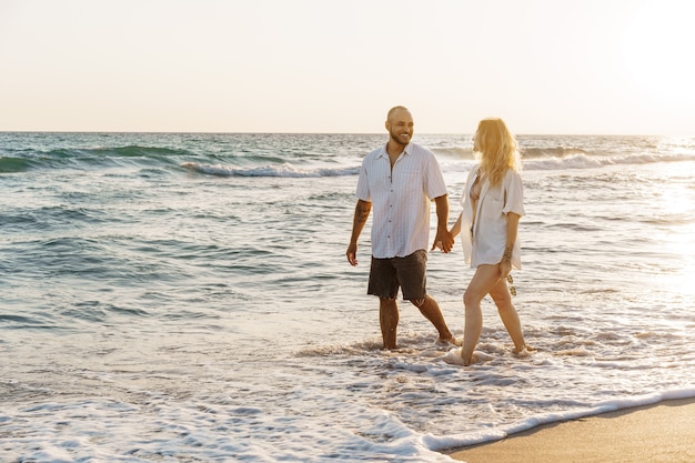 Young beautiful couple walking on beach near sea