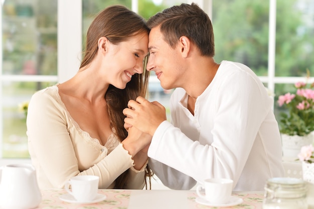 Young beautiful couple with cups of tea in the kitchen