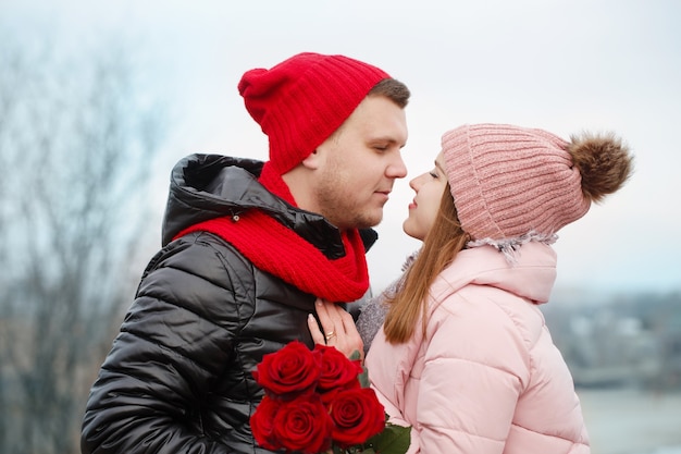 Young beautiful couple with red roses outdoors