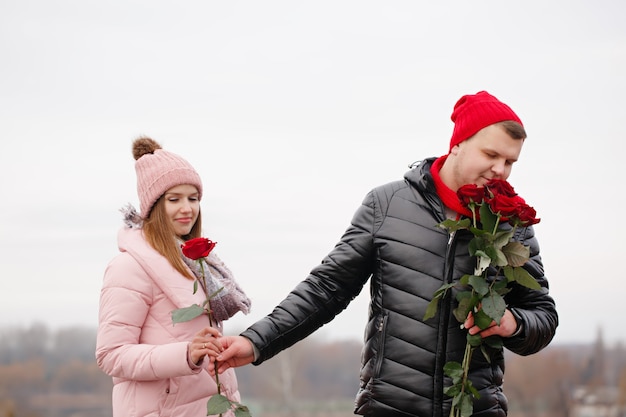 屋外で赤いバラと若い美しいカップル