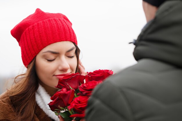 Giovane bella coppia con rose rosse all'aperto