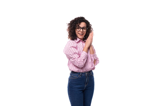 Photo young beautiful curly brunette woman in pink shirt posing against background with copy space