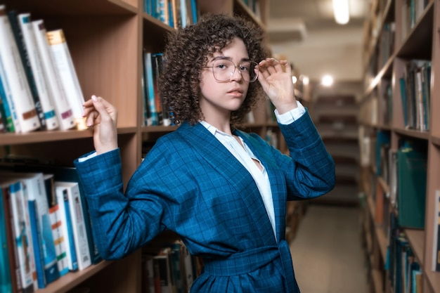 Young beautiful curly girl in glasses and a blue suit