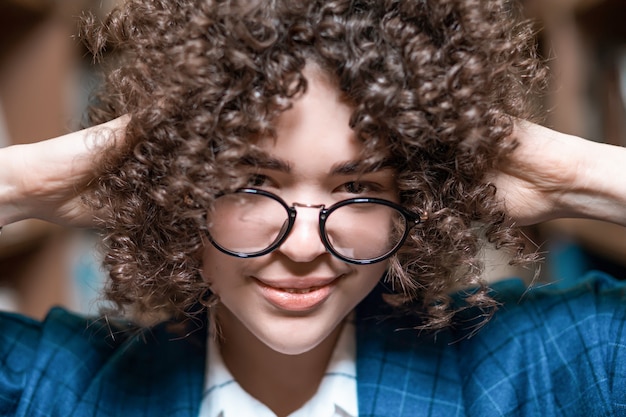 Young beautiful curly girl in glasses and a blue suit