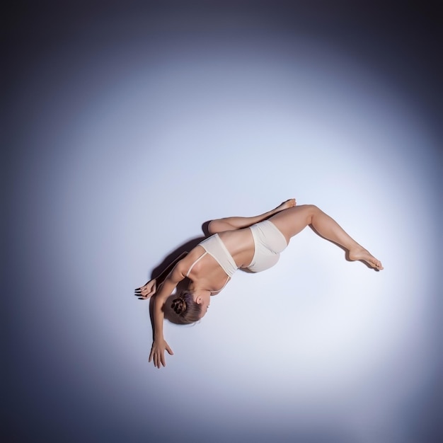 Young beautiful dancer in beige swimwear dancing on lilac background