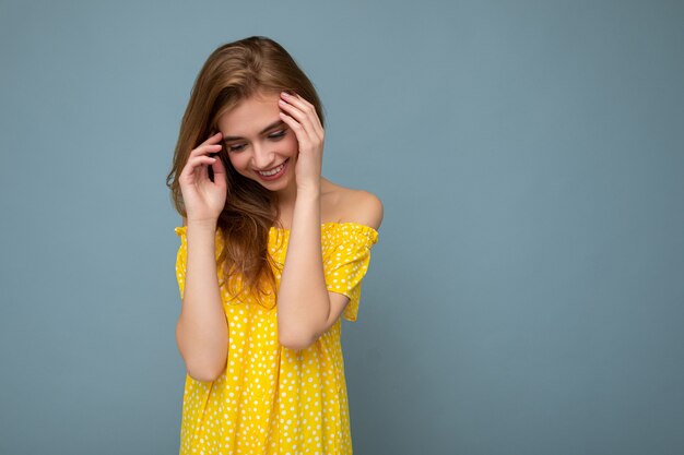 Young beautiful dark blonde woman with sincere emotions isolated on background wall with copy space