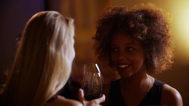 Young beautiful diverse women drinking red wine at luxury bar