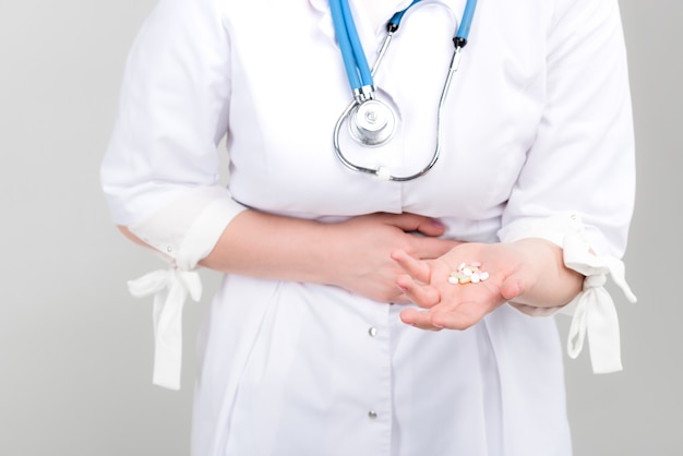 Young beautiful doctor in her uniform holding pills