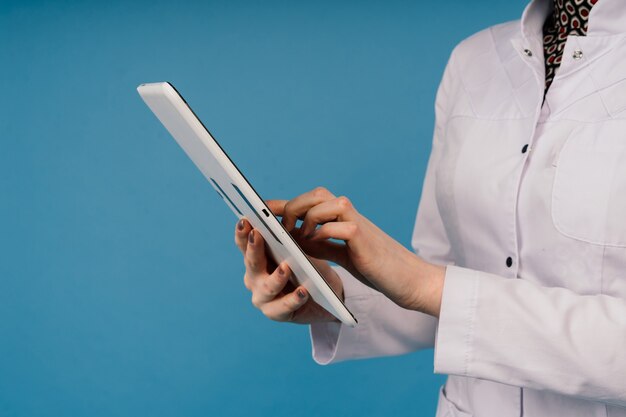 Young beautiful doctor woman in lab coat, studio shot, blue background