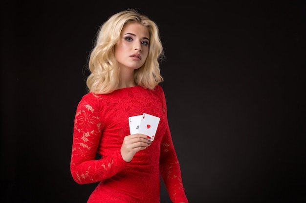 Фото Молодая красивая эмоциональная женщина с картами в руках на черном фоне в студии покера