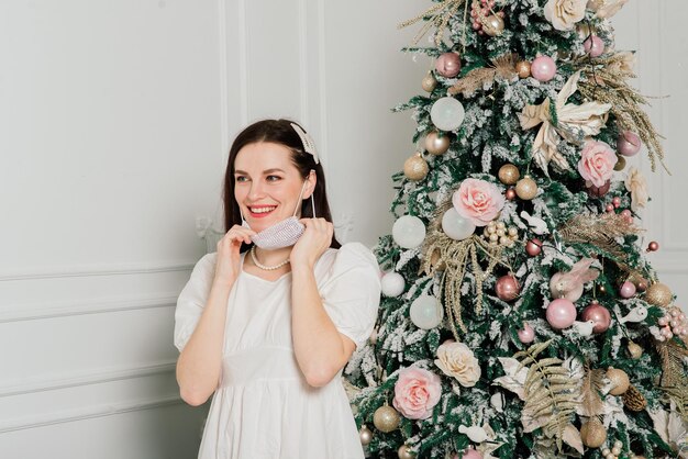 Giovane bella donna europea in maschera medica con regali di festa a casa quarantena coronavirus