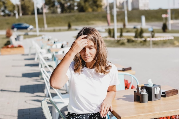 若い美しいヨーロッパの女性は、カフェのテラスで夏に座っています