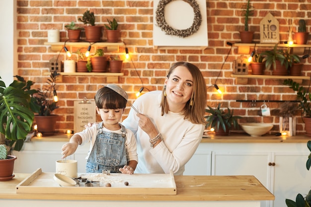 Young beautiful family having fun and cooking in the sunny kitchen