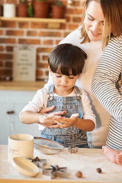 Young beautiful family having fun and cooking in the sunny kitchen