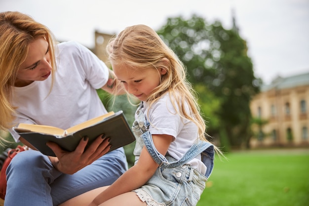 Giovane bella famiglia che trascorre del tempo sull'erba verde nel parco con un grande libro