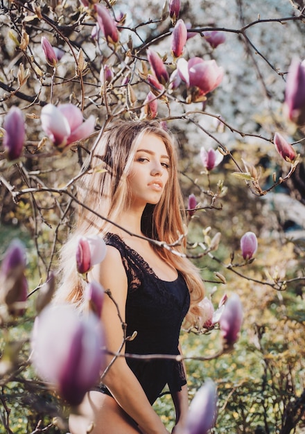 Young beautiful fashionable girl model posing in blossom magnolia spring fashion concept