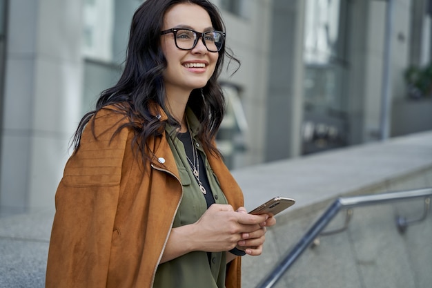 Young beautiful and fashionable woman wearing eyeglasses using her smartphone chatting with friend