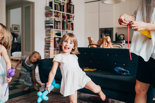 Young beautiful female child indoor at home playing with baloon smiling