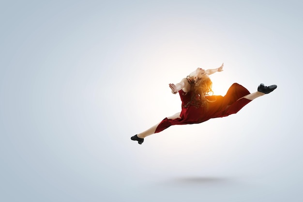 Молодая и красивая танцовщица в красном платье в прыжке. Смешанная техника