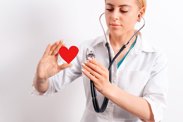 Giovane e bella dottoressa che tiene in mano un cuore di carta rossa trapiantologia e salute