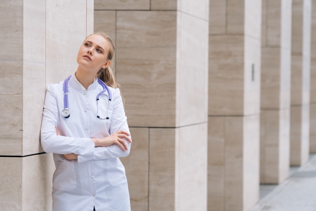 A young beautiful female doctor holds a stethoscope on an isolated white space.