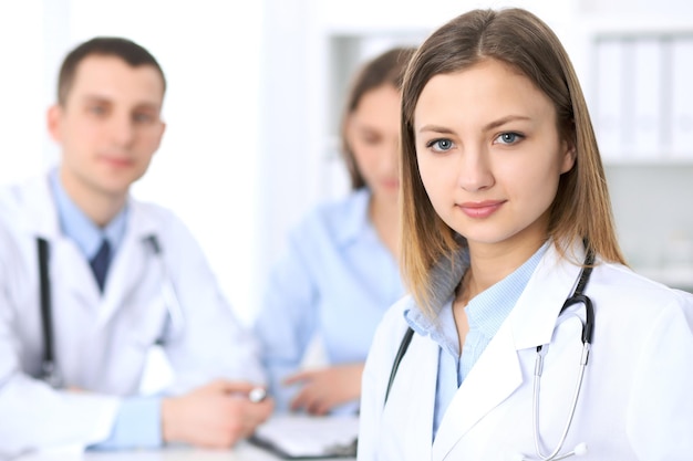 Giovane bella dottoressa sorridente sullo sfondo con il paziente in ospedale. concetto di servizio medico di alto livello e qualità.