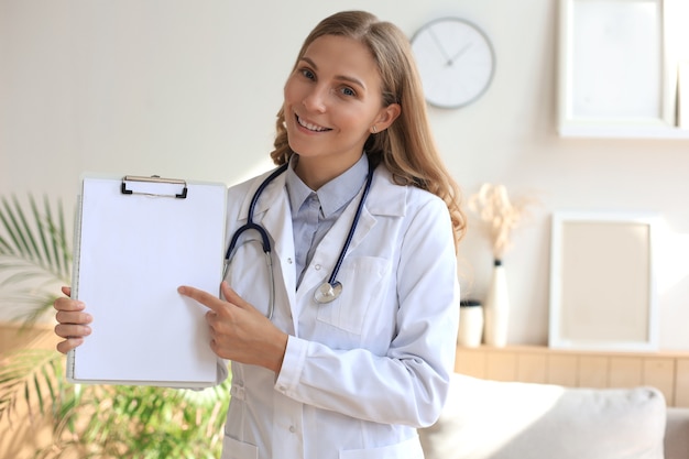 Phonendoscope와 흰색 코트에 젊은 아름 다운 여성 의사. 의사는 환자와 인터넷 대화를 통해 화상 통화를 상호 작용하여 온라인 상담에 도움을 줍니다.