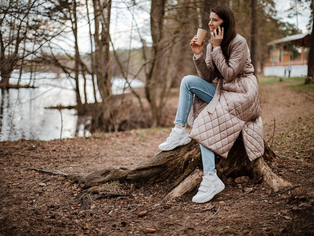 Young beautiful female drinking coffee talking on phone