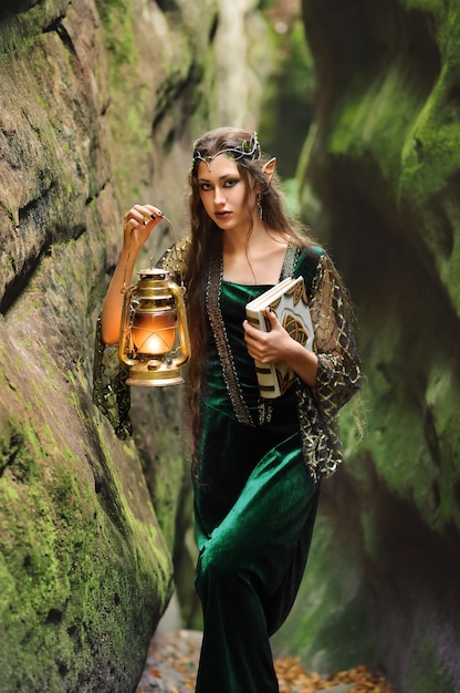 Young beautiful female elf walking through the forest with a book and a lantern 