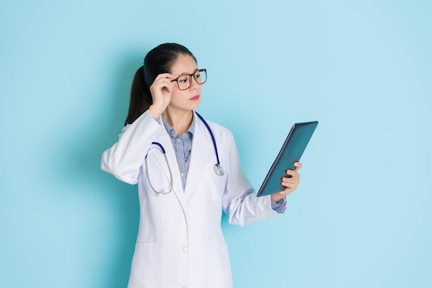 young beautiful female physician checking tablet in her hand and checking it carefully.