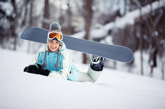 Young beautiful female snowboarder resting on ski slope