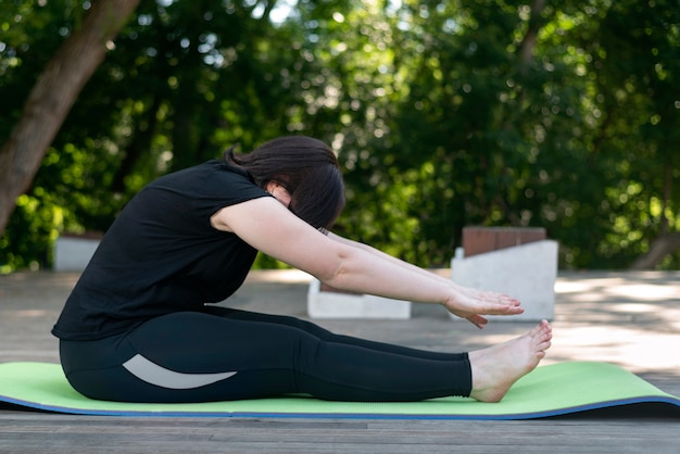 Young beautiful flexible girl makes a lean forward with her hands from a sitting position