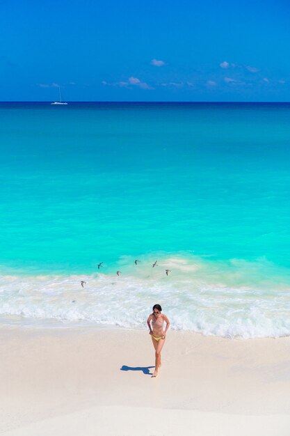 Young beautiful girl on the beach at shallow tropical water top view