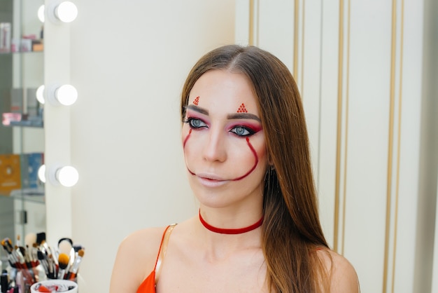 A young beautiful girl in a beautiful festive clown makeup for the Halloween holiday. Happy Halloween concept.