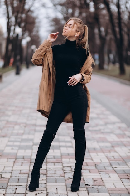 Young beautiful girl in a beige jacket posing on the streets of the city. clothing advertisement