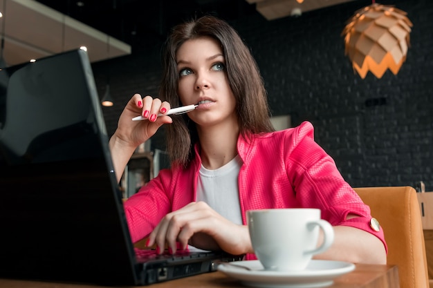 若い、美しい少女、実業家、カフェに座っているとラップトップに取り組んで