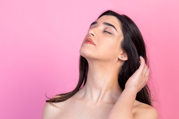 Young beautiful girl closed her eyes and standing on pink background High quality photo