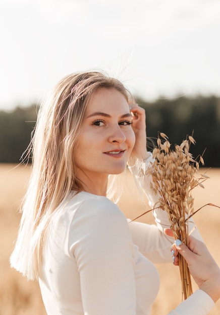 A young beautiful girl in a denim skirt walks through a wheat field on a sunny day