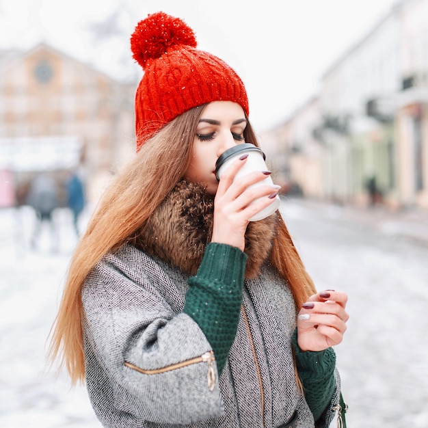 Молодая красивая девушка пьет горячий кофе в зимний холодный день