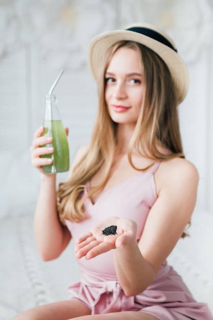 Young beautiful girl drinks a healthy green drink with Basil seeds through a reusable metal tube. The concept of healthy nutrition, environmental friendliness and zero waste. Toning.