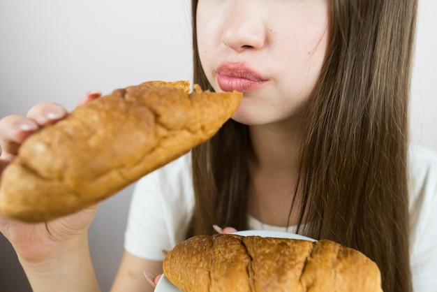 写真 クロワッサンを食べている美しい若い女の子クロウサントを食べている女性の口