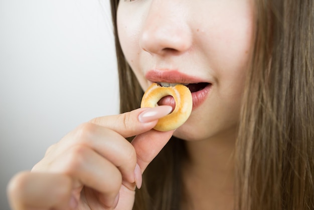 Foto giovane bella ragazza che mangia bagel close-up foto del raccolto attraente bruna donna sexy che mangia una deliziosa ciambella