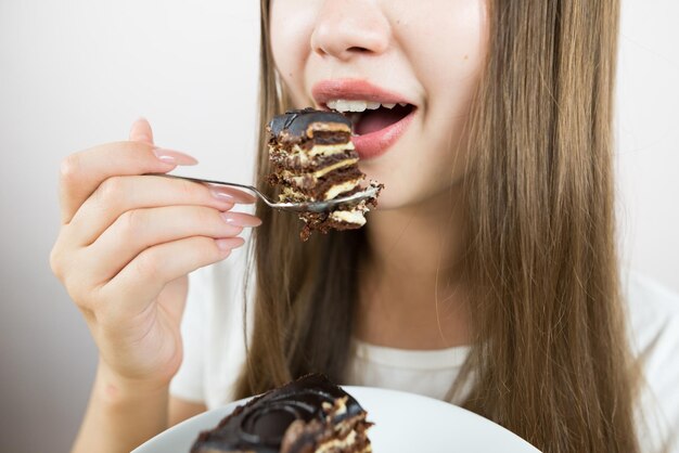 Foto giovane bella ragazza che mangia una torta close-up foto del raccolto bocca della donna che mangia un pezzo di torta